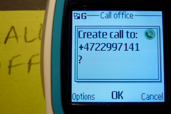 Close-up of a single post-it with handwritten contact information, ready to be touched by the phone